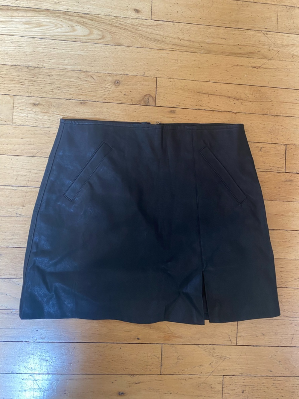 Olivaceous black faux leather mini skirt. Two front pockets. Zipper in back. Sm.